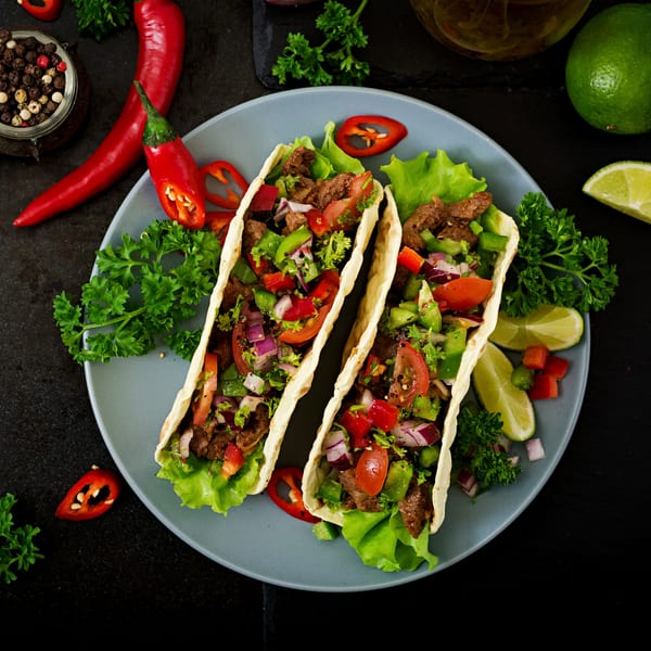 Two Zapata's beef tacos with lettuce, tomatoes, onions, and peppers on a blue plate.