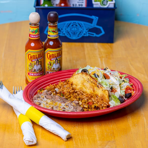 A Zapata's Mexican dish with rice, beans, a fried pastry, and salad, with two Cholula hot sauces.
